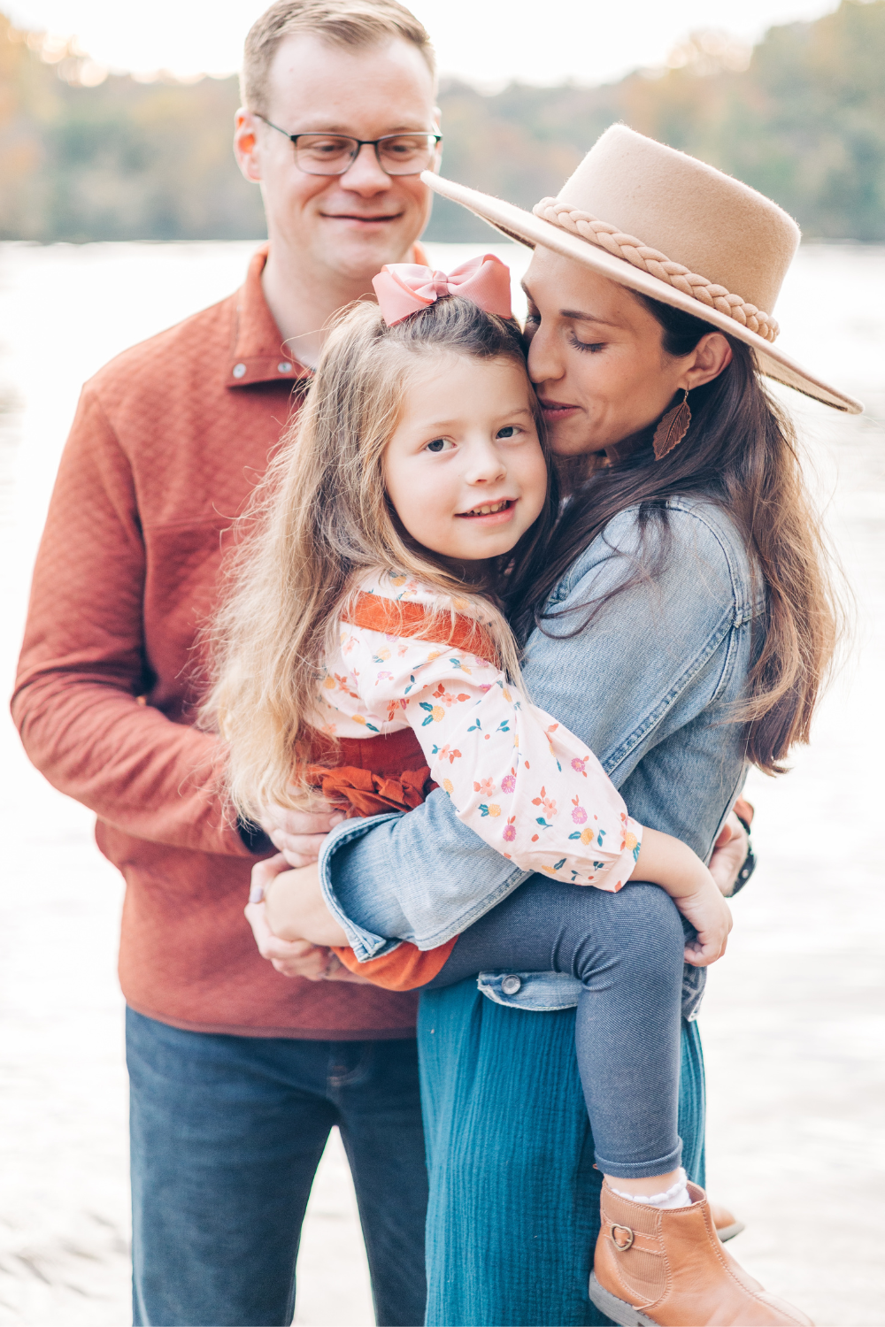 Parents embracing their child near water wearing coordinated neutral outfits for What to Wear for Family Pictures That Feel Natural