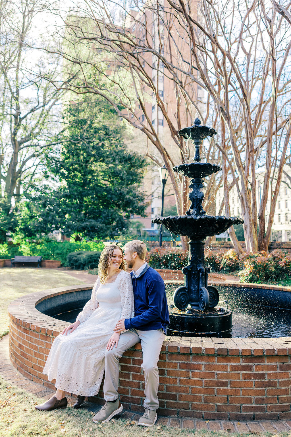 Couple seated by a fountain in downtown Columbia during a romantic engagement session