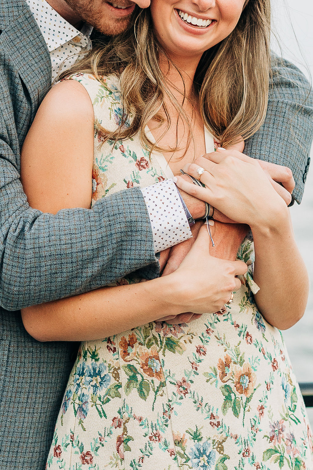 Close-up engagement photo highlighting a ring and affectionate embrace during a coastal session