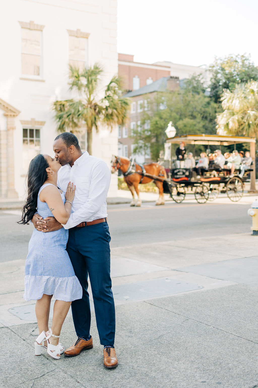 Romantic engagement session featuring a horse-drawn carriage in the background in Charleston