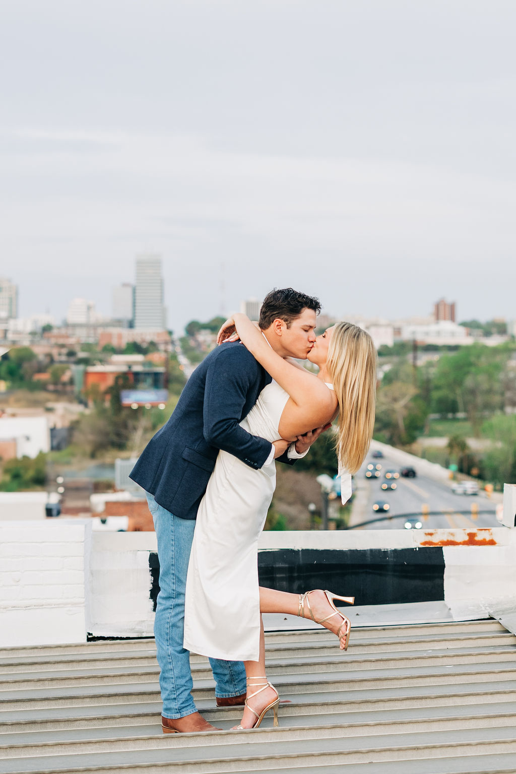 Urban engagement session in Columbia SC featuring a couple kissing with skyline views