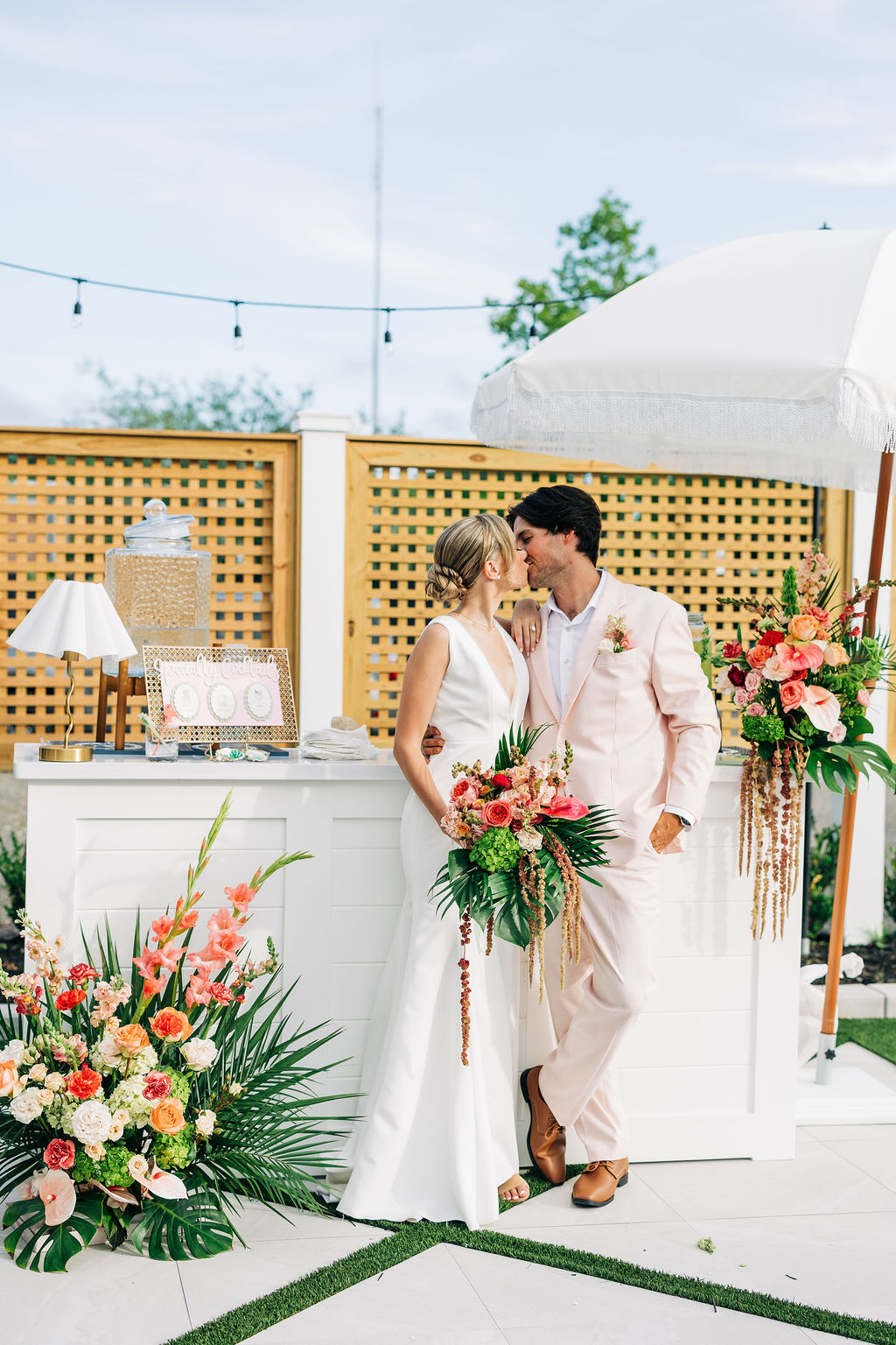 Bride and groom walking toward a floral ceremony arch surrounded by palm trees