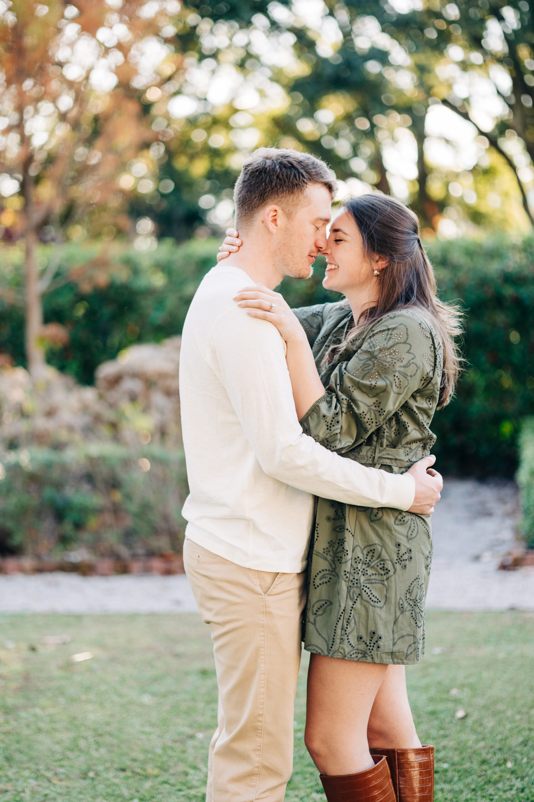 Couple embracing closely with their foreheads touching, surrounded by greenery of a historic home in SC