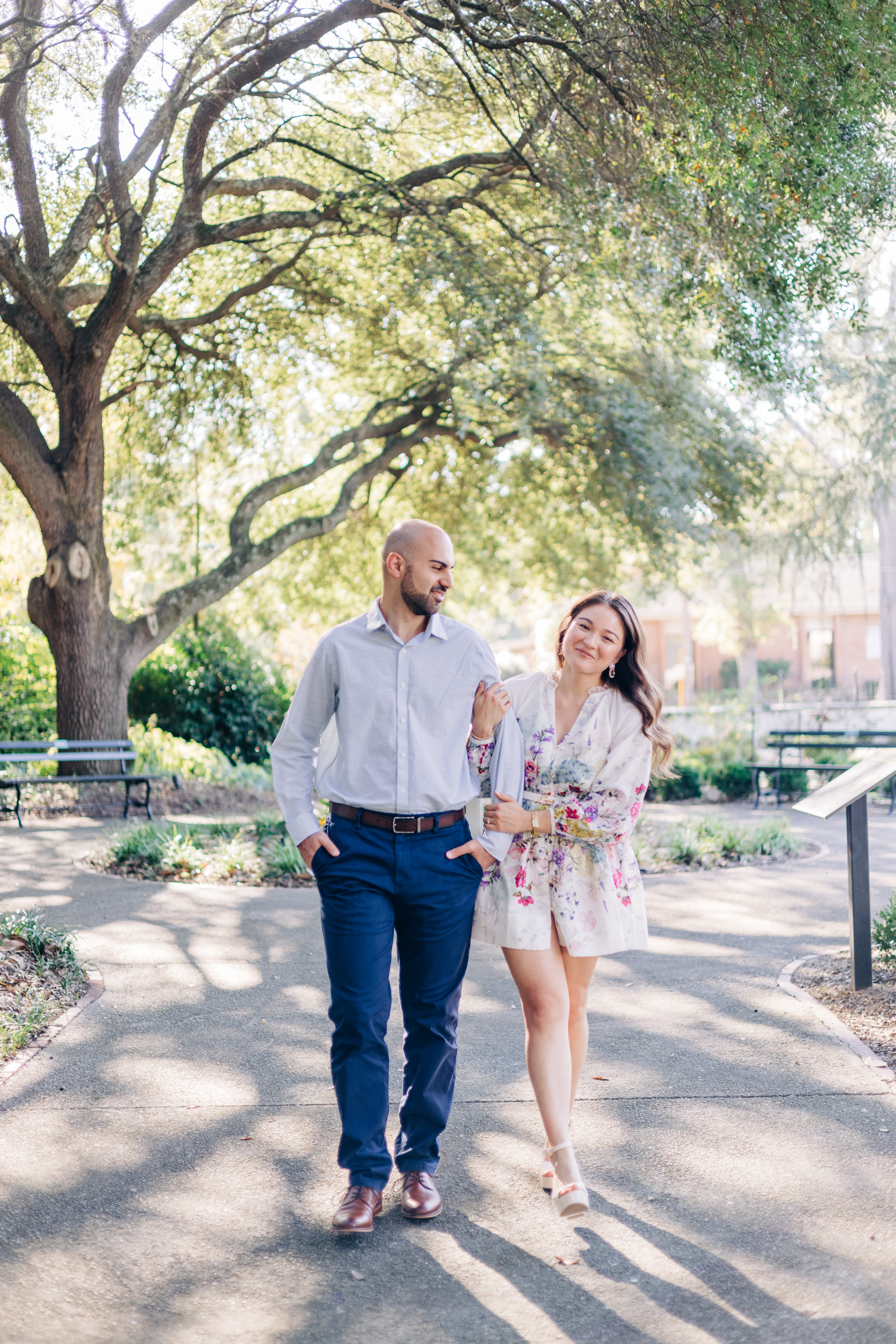 Couple smiling while walking together, with the woman holding onto her partner’s arm