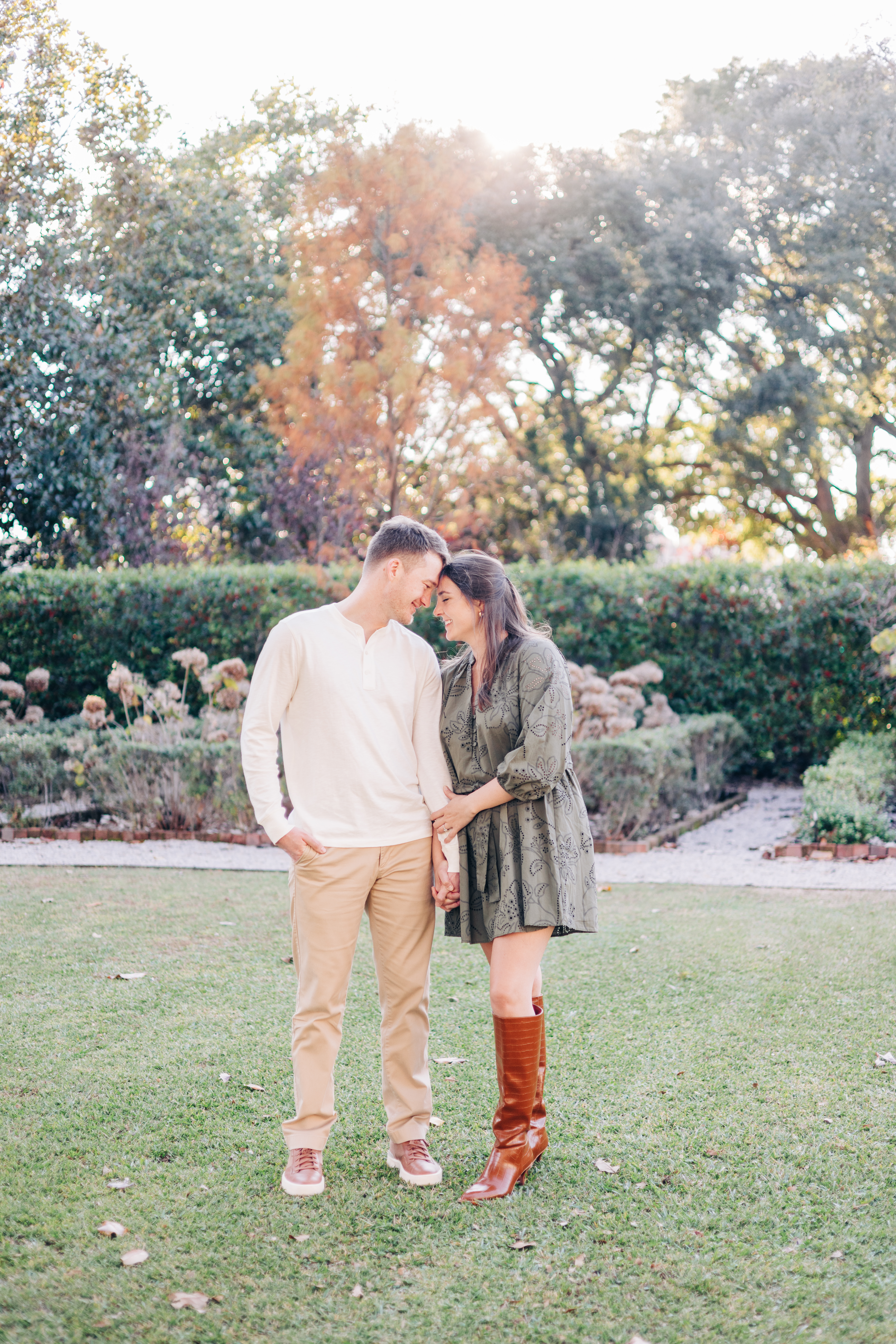 Couple holding hands and leaning their foreheads together in a garden setting at the historic homes. 