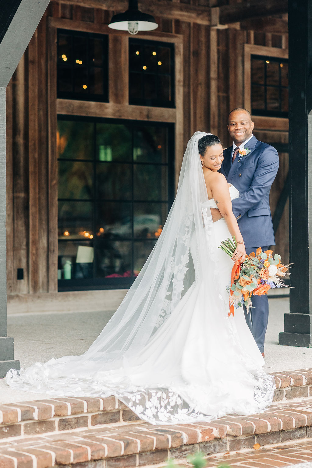 Newlyweds embracing outside rustic venue